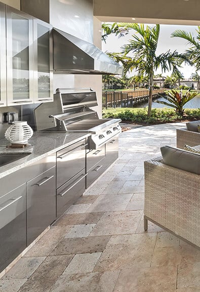 Fancy stainless steel kitchen on patio with pool view.