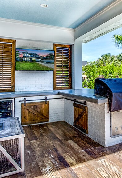 Patio kitchen with TV and pool.