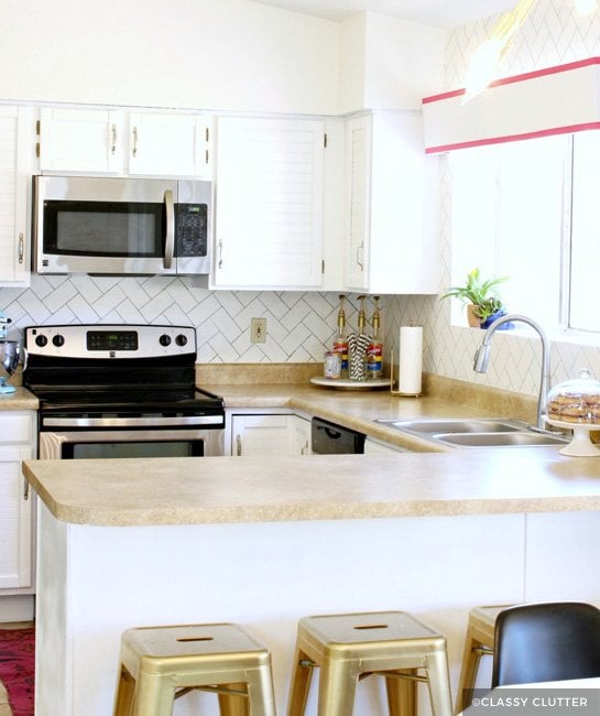 Painted white kitchen cabinets with white tile backsplash and gold stools