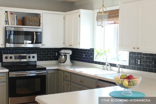 White painted cabinets with black tile backsplash