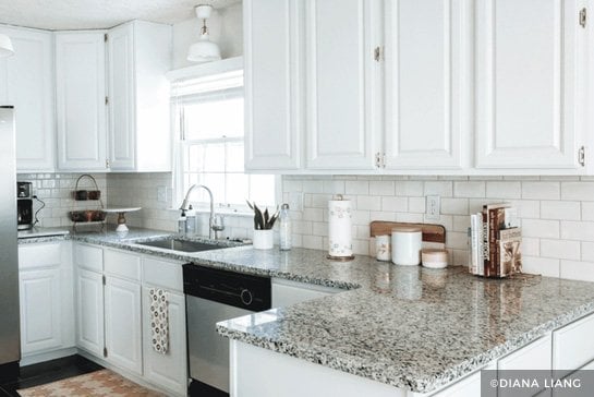 White painted cabinets with white tile backsplash and granite countertop