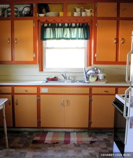 Orange kitchen cabinets with green curtain