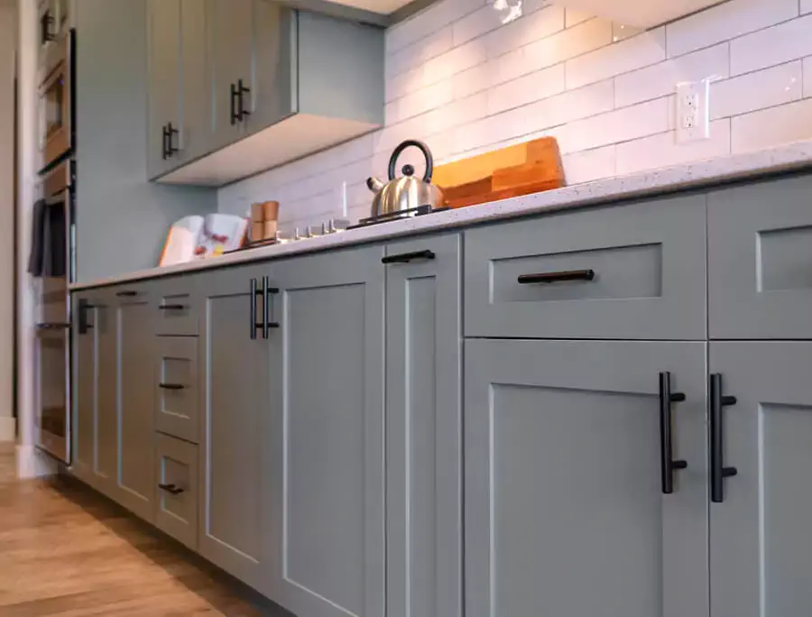 Grey-painted Shaker style cabinets with black hardware.