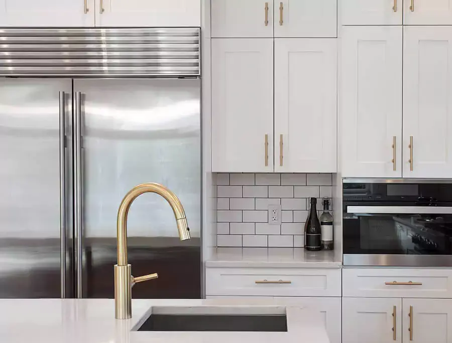 Modern white Shaker style cabinets with gold hardware.