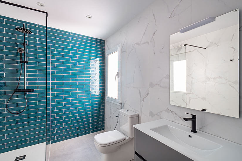 White bathroom with aqua blue subway tile in shower.