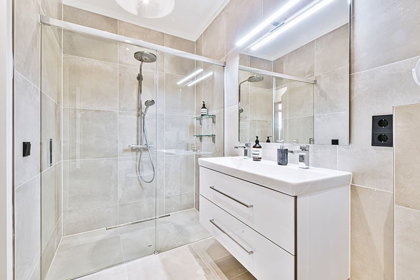 Small bathroom with white floating vanity and large glass shower door.