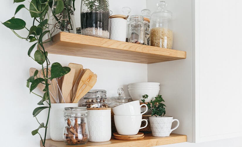 Spice jars and mugs stored on open kitchen shelves.
