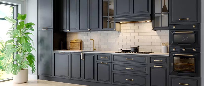 Modern kitchen with navy blue thermofoil cabinets with gold accents.