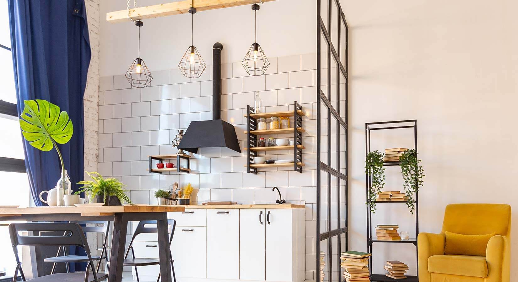 Small one-wall kitchen with white cabinets, wood countertops, and cage pendant lights suspended from wood beam.