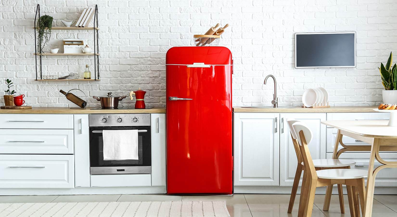 Small single-wall kitchen with white cabinets and bright red refrigerator.