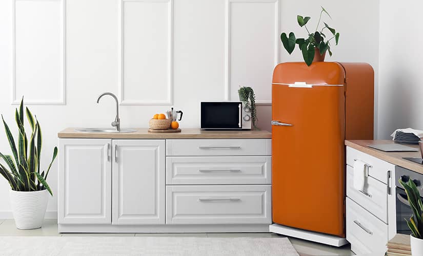 Transitional kitchen with retro orange refrigerator.