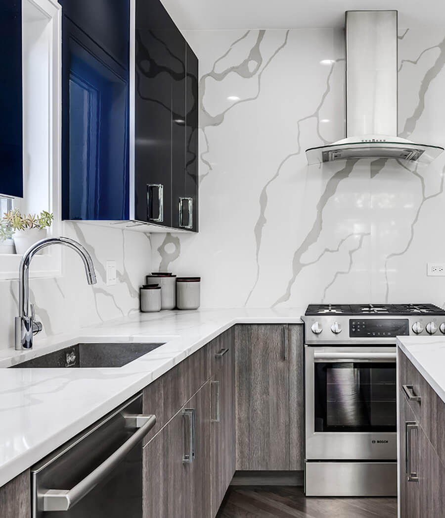 Two-tone kitchen with marble countertop and backsplash.