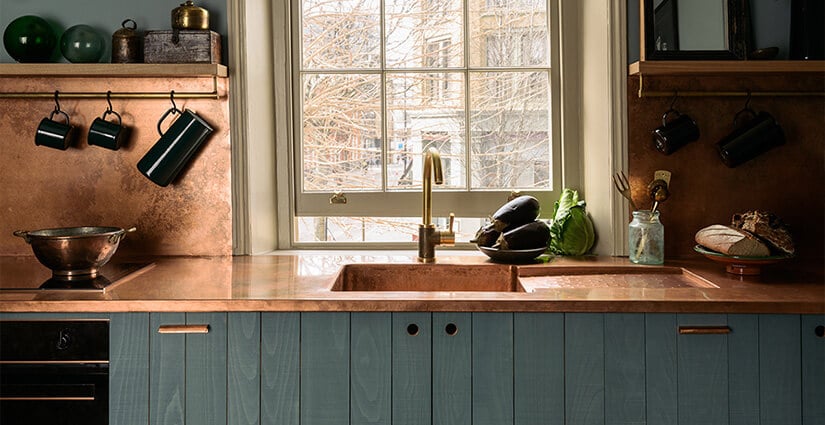 Kitchen with blue wood cabinets and copper countertop and backsplash.
