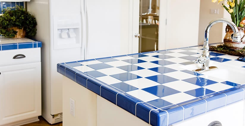 Kitchen with white cabinets and blue and white-checkered tile countertop.